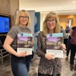 Picture of Clare Sim and Claire Wardle showing the Conference brochure